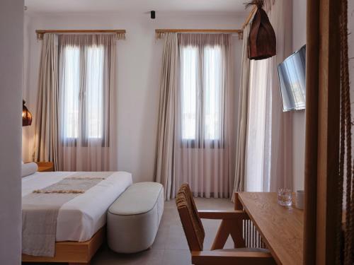 a bedroom with a bed and a desk and windows at Le Palme Mykonos in Klouvas