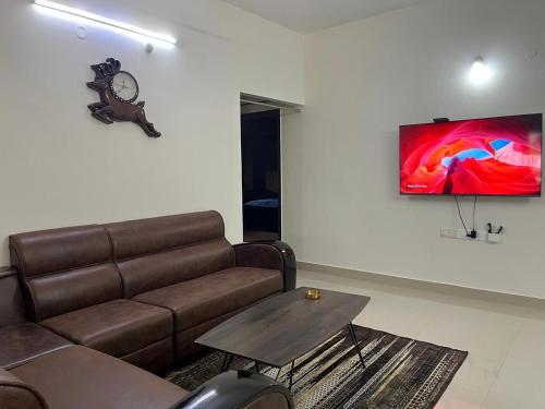 a living room with a couch and a clock on the wall at Naidu Nilayam in Secunderabad