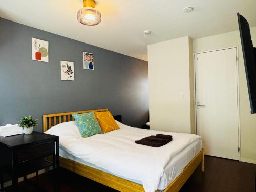 a bedroom with a bed with white sheets and a table at Lucky you! YOTSUYA in Tokyo