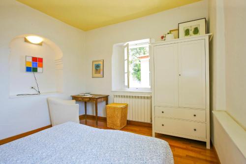 a bedroom with a bed and a cabinet and a table at Appartamento Ronco in Ghiffa