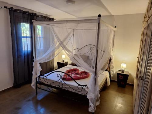 a bedroom with a canopy bed with white curtains at Villa Cœur Lagune Piscine 4 chambres in Nianing