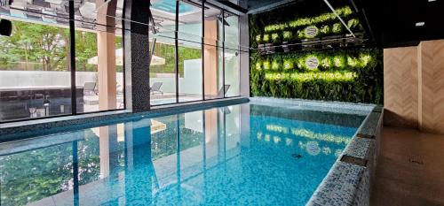 ein Swimmingpool mit einer Wand aus grünen Pflanzen in der Unterkunft HolidayHomePL Sea & Forest D344 z sypialnią, basen, spa, gym GRATIS in Misdroy