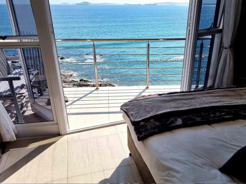 a bedroom with a view of the ocean from a balcony at Crystal Lagoon Lodge in Langebaan