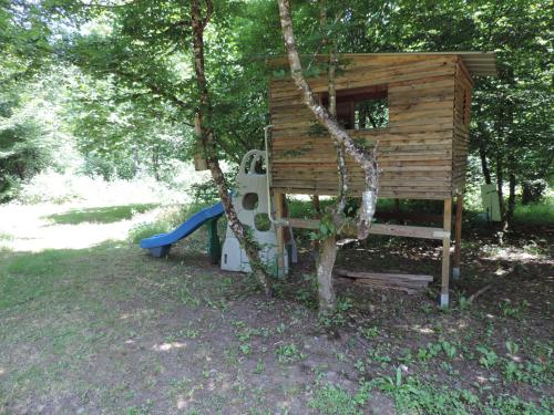 a wooden tree house with a playground in a park at Emeraude aux 1000 Etangs in Belonchamp