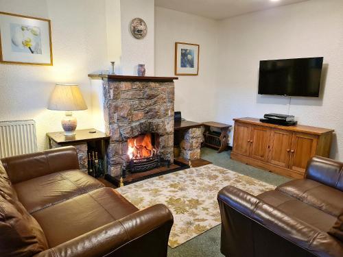 ein Wohnzimmer mit Kamin und Fernseher in der Unterkunft Oakleigh Cottage in Llangelynin
