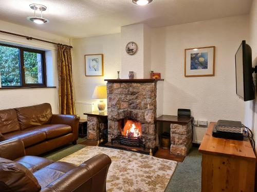 ein Wohnzimmer mit Couch und Kamin in der Unterkunft Oakleigh Cottage in Llangelynin