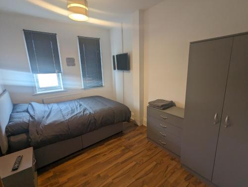 a bedroom with a bed and a dresser and windows at The Noisy Rooms in Southampton