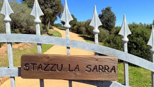 a wooden sign on a gate with a path at Stazzu La Sarra in Cannigione