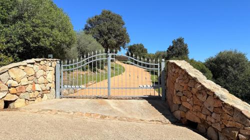 a gate in a stone wall with a fence at Stazzu La Sarra in Cannigione
