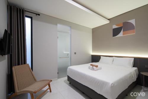a hotel room with a bed and a chair at Cove Vaia in Bandung