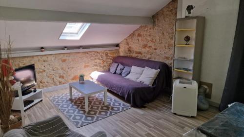 un salon avec un canapé violet et une télévision dans l'établissement Appartement à 1km de Sarlat à la campagne, à Sarlat-la-Canéda