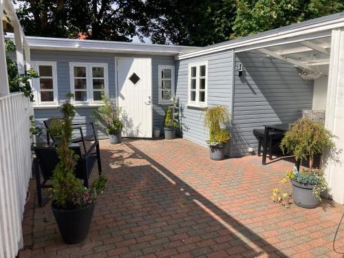 a shed with a table and benches and potted plants at Indbydende bed & breakfast med dejlig gårdhave in Randers