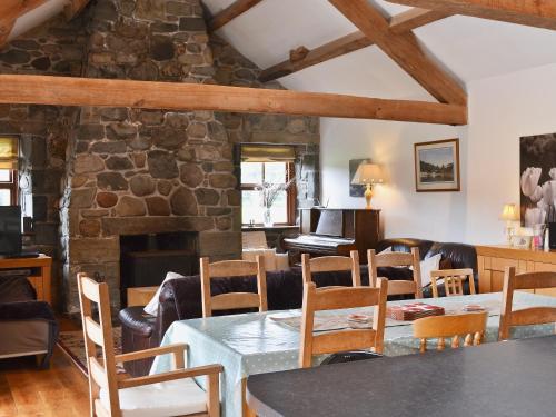 a living room with a table and chairs and a piano at Glanrafon Isaf in Llanwnda