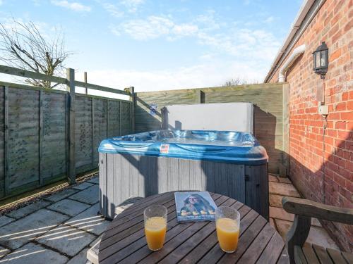 a hot tub and a table with two glasses of orange juice at One Chainbridge Barns in Skegness