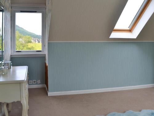 a bathroom with a blue wall and two windows at River Mill House in Ballachulish