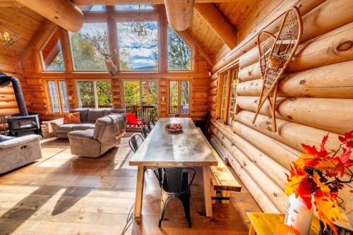 een grote woonkamer met een tafel in een blokhut bij L'Antaya - SPA Mountain in Saint-Philémon