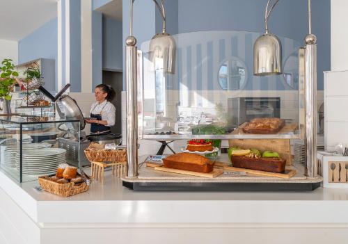 a woman standing behind a bakery counter with bread and pastries at Hotel Panorama in Cattolica