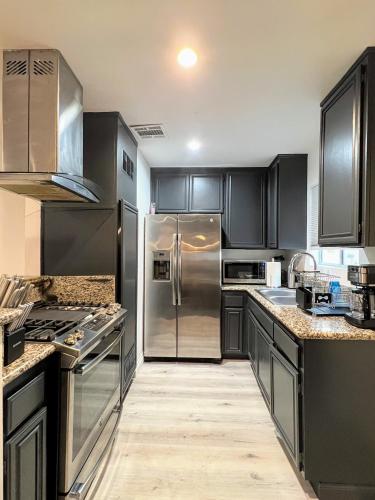 a kitchen with black cabinets and a stainless steel refrigerator at Hollywood Black Habitat in Los Angeles