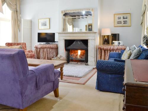 a living room with purple chairs and a fireplace at Crogen Coach House - Oqr in Llandrillo