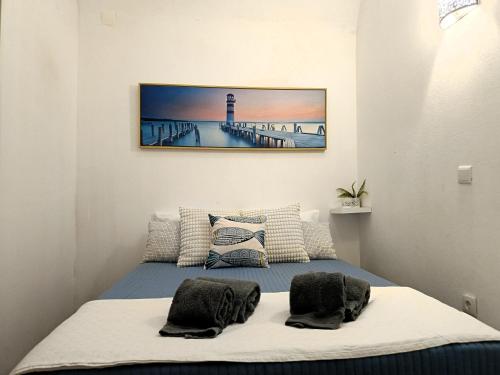 a bedroom with a bed with a picture on the wall at Casa Ibaía, típica e acolhedora no centro de Olhão in Olhão