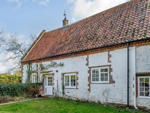 an old white cottage with a red roof at The Barn in Hunstanton