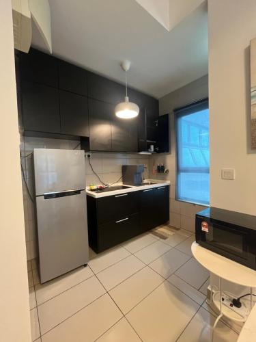 a kitchen with black cabinets and a refrigerator at IOI Retreat at Conezion near IOI City Mall-Free Netflix in Putrajaya