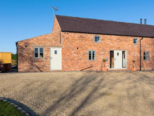 a brick barn with white doors and a gravel driveway at The Foundary - Uk36319 in Whitchurch