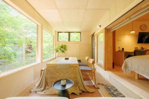 a room with a table and a bed and a window at Cooee Yamanakako in Yamanakako