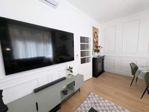 a living room with a large flat screen tv on a wall at VENI VEDI VICHY climatisé, 50m2 coeur de ville in Vichy