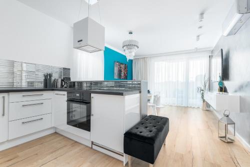 a kitchen with white cabinets and a black stool at Apartament AQUAMARIN Sarbinove Prestige by BALTIC CLUB in Sarbinowo