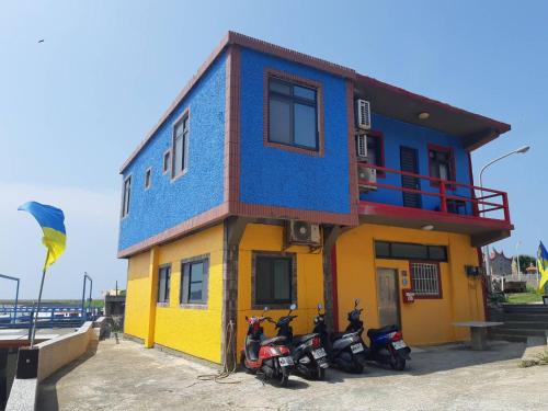 un edificio colorido con motocicletas estacionadas frente a él en Taipei Homestay, en Juguang