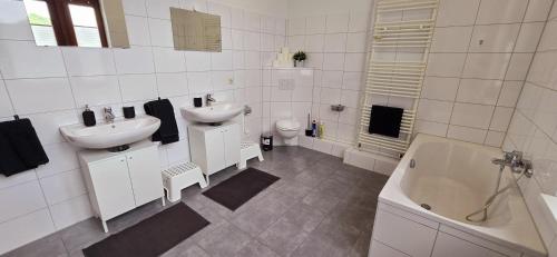 a white bathroom with two sinks and a tub and a toilet at 3BR - Bremerhaven Apartment in Bremerhaven