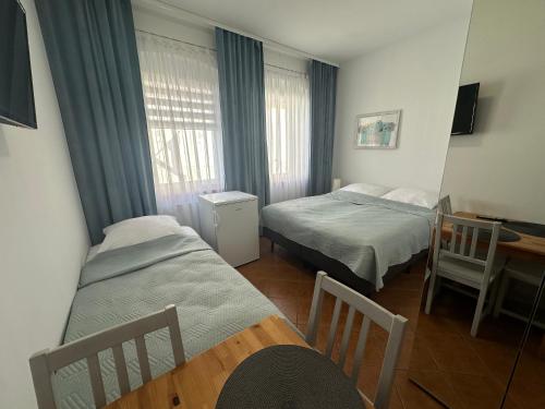 a small room with two beds and a table and a desk at Domki i POKOJE PLAŻOWE in Darlowko