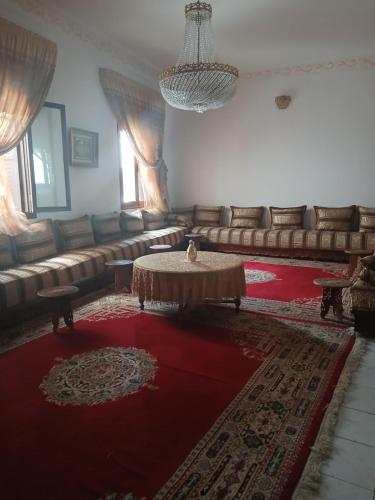 a living room with couches and a table on a red rug at Casa Medina Sanaa in Tetouan