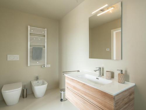 a bathroom with a sink and a toilet and a mirror at Appartamento Melograno "A Casa Felice" in Pietra Ligure