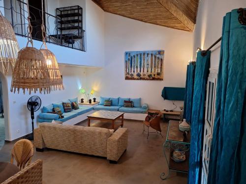 a living room with a blue couch and a table at Villa Cœur Lagune Piscine 4 chambres in Nianing