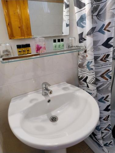 ein Badezimmer mit einem weißen Waschbecken und einem Spiegel in der Unterkunft Mpezas Studios in Igoumenitsa