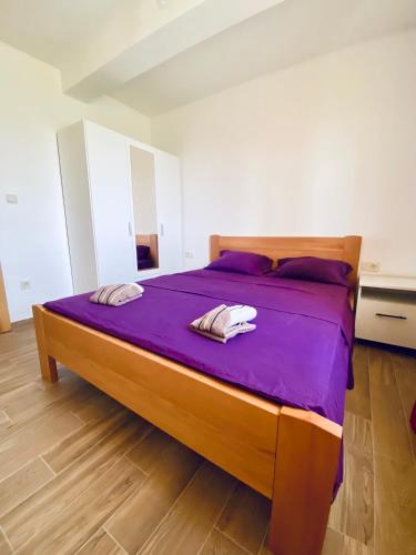 a bed with purple sheets and two towels on it at Talia Apartments in Budva