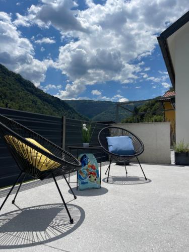 two chairs sitting on a patio with mountains in the background at HOLIDAY HOUSE - River Bača in Most na Soči