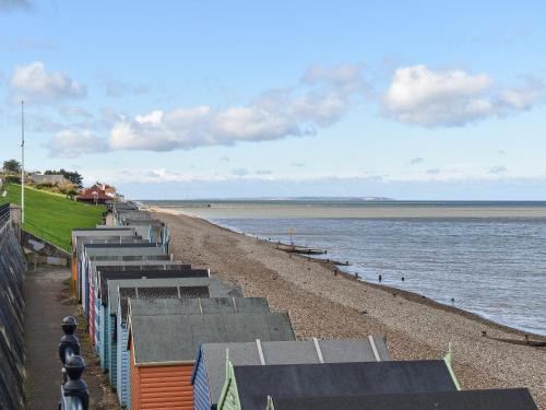 a beach with a row of benches and the water at La Casita in Herne Bay