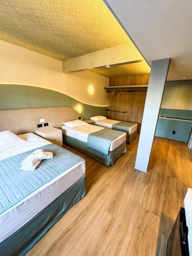 a hotel room with two beds and wooden floors at Hotel Zata - Premium in Criciúma