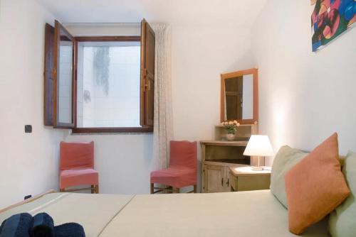 a bedroom with a bed and two chairs and a window at Casa del sole in Lavena Ponte Tresa