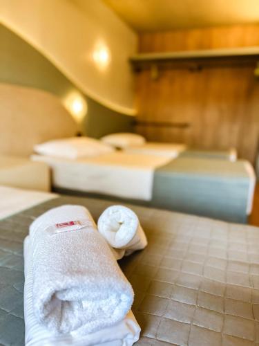 a room with two beds with towels on the floor at Hotel Zata - Premium in Criciúma