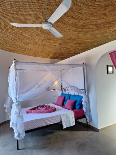 a bedroom with a canopy bed with pink and blue pillows at Villa Cœur Lagune Piscine 4 chambres in Nianing