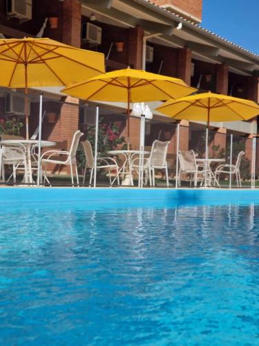 a pool with chairs and umbrellas in front of a hotel at Pousada Ponta do Lobo in Balneário Camboriú