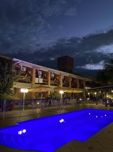 a large blue pool in front of a building at night at Pousada Ponta do Lobo in Balneário Camboriú