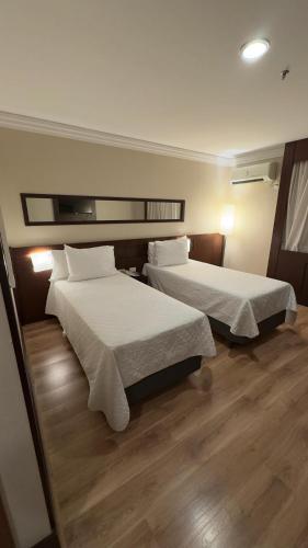 a hotel room with two beds and wooden floors at Transamerica Executive Congonhas in Sao Paulo