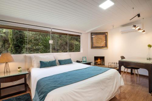a bedroom with a bed and a desk and a piano at Pousada Apple House Campos do Jordao in Campos do Jordão
