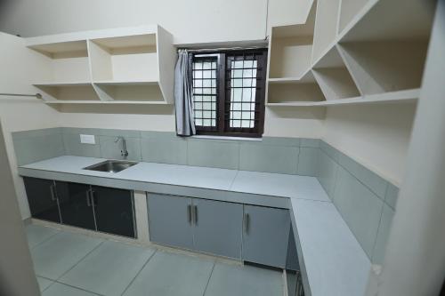 a white kitchen with a sink and a window at Tranquil Rest House in Trichūr