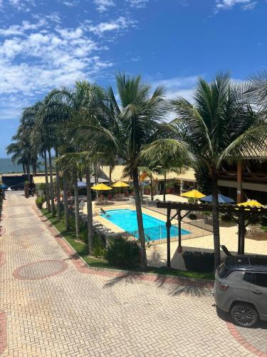 a resort with a pool with palm trees and umbrellas at Pousada Ponta do Lobo in Balneário Camboriú